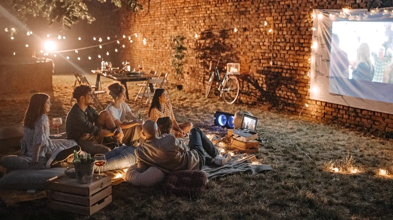 Friends watching an outdoor movie projected on a sheet at night